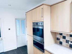 uma cozinha com um forno preto e armários em Comfy House Near The City Centre em Nottingham