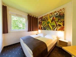 ドルトムントにあるB&B HOTEL Dortmund-Messeのベッドルーム1室(壁に絵画が描かれたベッド1台付)
