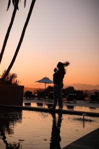 a woman standing by a pool with the sunset in the background at Pezula Nature Retreat in Knysna