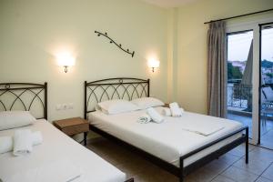 two beds in a room with a balcony at Konstantinos Hotel & Apartments 2 in Nydri