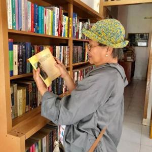 een vrouw die een boek leest in een bibliotheek bij Rumah Inyiak Aguang in Baso