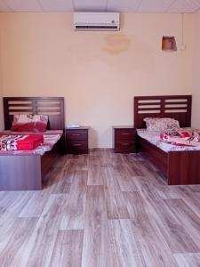 two beds in a room with wooden floors at استراحة وزنه in Buraydah