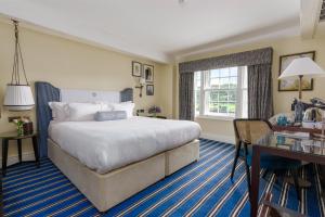 um quarto de hotel com uma cama grande e uma secretária em The Relais Henley em Henley on Thames