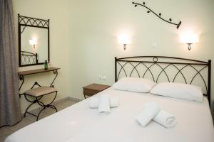 een slaapkamer met een bed met witte lakens en een spiegel bij Konstantinos Hotel & Apartments 2 in Nydri