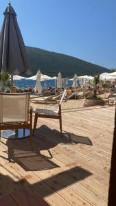 a group of chairs and an umbrella on a beach at Yachthafen Marina Bar in Herceg-Novi