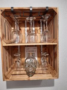 une étagère en bois avec des verres à vin en verre dans l'établissement Charmante maison rénovée, proche lac et centre-ville, à LʼIsle-Jourdain