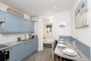 a kitchen with blue cabinets and a table with plates on it at Rame in Looe