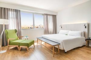 a hotel room with a large bed and a green chair at ARTIEM Madrid in Madrid