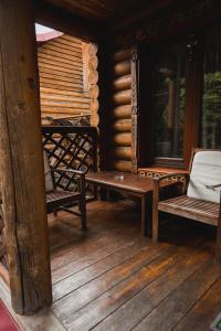 eine Veranda mit zwei Stühlen und einer Bank auf einer Kabine in der Unterkunft Villa Garden Hotel in Solotschyn
