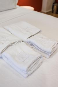 un grupo de toallas blancas apiladas en una cama en K2 Suites Kalamata, en Kalamata
