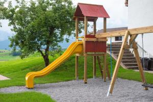 a wooden playground with a slide and a swing at Panoramablick Heimen in Hopferau