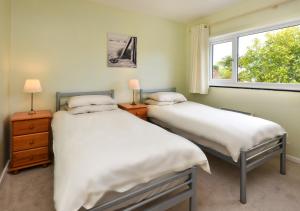 two twin beds in a room with a window at Mor Gragen in Abersoch