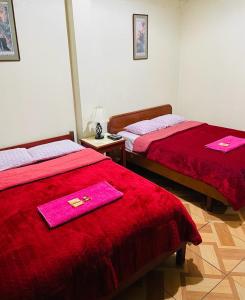 2 Betten in einem Zimmer mit rosa Handtüchern darauf in der Unterkunft KORICANCHA in Lima