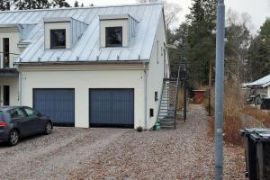 una casa blanca con dos puertas de garaje y un coche en Lägenhet i villa, en Bålsta