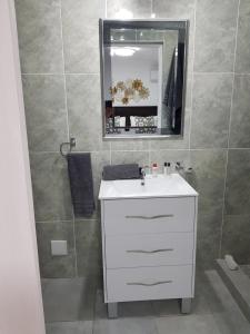 uma casa de banho com um lavatório branco e um espelho. em Arcangeli Wines em Botrivier