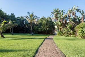 a brick path through a park with palm trees at La Ballito 305 in Ballito