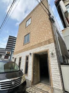 een auto geparkeerd voor een bakstenen gebouw bij PAThouse台东区店 in Tokyo