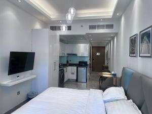 a bedroom with a white bed and a kitchen at Tranquil Studio Marina View in Dubai