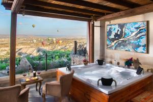 a bath tub in a room with a large window at Simera in Cappadocia - Special Class in Uçhisar