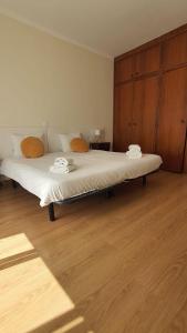 a large white bed in a room with wooden floors at Macrisbete 2 in Fátima