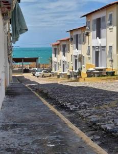 una calle adoquinada junto a los edificios y el océano en Alugo apartamento na praia, en Caucaia