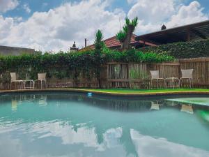 a swimming pool with chairs and a wooden fence at The Melville Quarters in Johannesburg