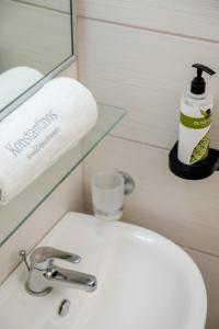 a bathroom sink with a bottle of soap and a mirror at Konstantinos Hotel & Apartments 2 in Nydri