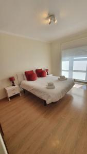 a bedroom with a large white bed with red pillows at Macrisbete 2 in Fátima