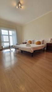 a large bed in a room with a wooden floor at Macrisbete 2 in Fátima