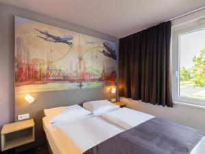 فندق بي&بي دوسلدورف-إيربورت في دوسلدورف: غرفة نوم بسرير مع لوحة على الحائط
