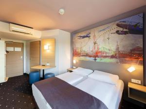 デュッセルドルフにあるB＆B ホテル デュッセルドルフ エアポートのベッド付きの客室で、壁には絵画が飾られています。
