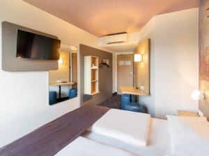 デュッセルドルフにあるB＆B ホテル デュッセルドルフ エアポートのベッド1台、壁掛けテレビが備わるホテルルームです。
