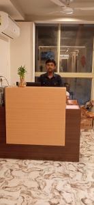 a man standing behind a counter in a room at Hotel Shaswat Inn in Ahmedabad