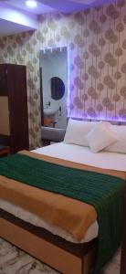 a bedroom with a bed with a green blanket and a mirror at Hotel Shaswat Inn in Ahmedabad