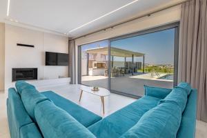 a large blue couch in a living room with a large window at Mont Fleury Resort in Koskinou