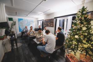 eine Gruppe von Menschen, die an einem Tisch mit einem Weihnachtsbaum sitzen in der Unterkunft Gjestehuset 102 in Longyearbyen