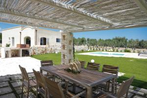 een patio met een houten tafel en stoelen bij Trulli Dimore - Villa Coco in Ostuni