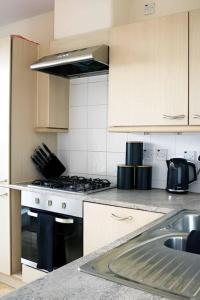 a kitchen with white cabinets and a stove top oven at Bright 2Bed Central Apartment in Milton Keynes