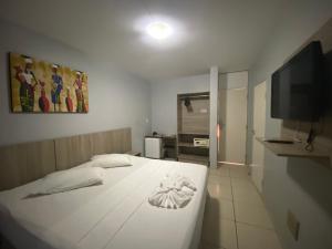 um quarto com uma cama branca e uma televisão de ecrã plano em Hotel Fortaleza Inn em Fortaleza