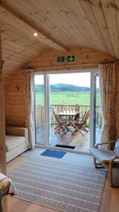 Beautiful Glamping Pod with Central Heating, Hot Tub, Garden, Balcony & views - close to Cairnryan - The Herons Nest by GBG في Glenluce: غرفة مع باب زجاجي منزلق كبير في كابينة