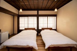 two beds in a room with two windows at GLOCE西会津 ふくの屋 l 古きを知り新しきを愉しむ l 築110年超の古民家が綴る心地よい宿 in Yanaizu