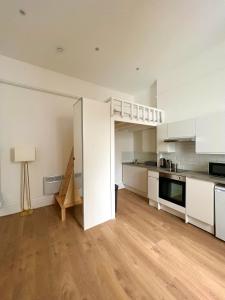 una cocina vacía con armarios blancos y suelo de madera en New modern studio flat, en Brighton & Hove
