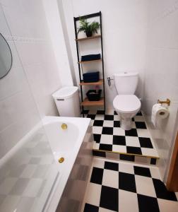 een badkamer met een toilet en een zwart-wit geruite vloer bij Cosy condo in Warschau