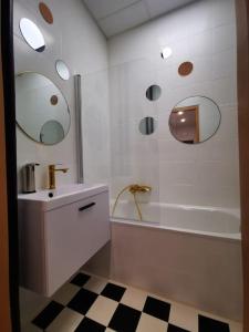 een badkamer met een bad, een wastafel en een spiegel bij Cosy condo in Warschau