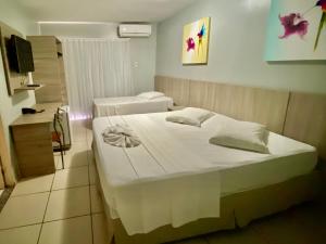 a bedroom with two beds and a television in it at Hotel Fortaleza Inn in Fortaleza