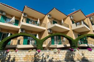 a large apartment building with green hedges in front of it at Konstantinos Hotel & Apartments 2 in Nydri