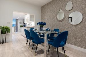 uma sala de jantar com uma mesa e cadeiras azuis em Luxury living away from home em Earlswood