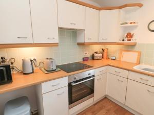 a kitchen with white cabinets and a stove top oven at 60B Castlegate in Berwick-Upon-Tweed