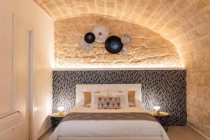 1 dormitorio con cama y pared de ladrillo en B&B Torre Canina suite & rooms, en Trani