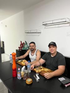 two men sitting at a table with food at Casa do Zafer in Sao Paulo